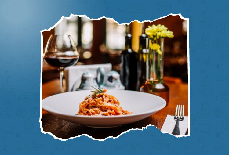Image of a delectable Italian pasta dish served in an authentic Italian restaurant in Delhi, complemented by a glass of red wine and fresh flowers.